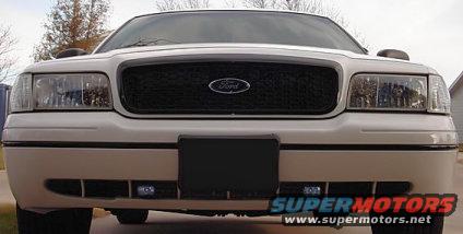 White 2000 Ford Crown Victoria front view with black grille and Ford logo. Headlights and lower fog lights are visible