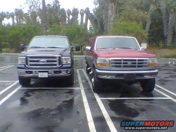 Red Ford SUV with chrome grille and headlights, parked next to a dark blue Ford truck