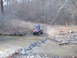 1999 Honda RANCHER - Riding an ATV through a stream in a wooded area.
