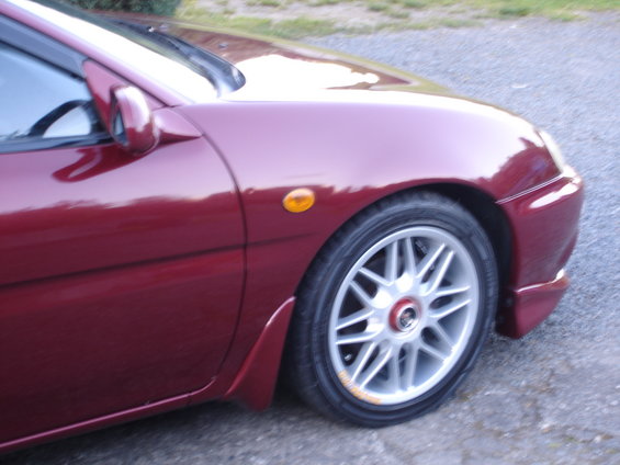 Red coupe's front fender, side mirror, and wheel