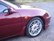 1993 Mazda MX-3 - Close-up of the front passenger side of a red coupe, showing the wheel and fender.