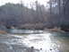 1999 Honda RANCHER - A natural scene of a river flowing through a wooded area with rocky shores.