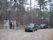 1999 Honda RANCHER - Two trucks and a trailer are parked on a gravel lot next to a bulletin board in a wooded area.