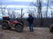 1999 Honda RANCHER - A red ATV is parked on a rocky trail with a person standing next to it, and another ATV visible in the background.