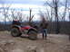 1999 Honda RANCHER - A red ATV is parked on a rocky trail with a person standing beside it, overlooking a wooded landscape.
