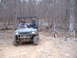 1999 Honda RANCHER - A utility vehicle with three occupants drives on a wooded trail near a sign indicating trail rules.