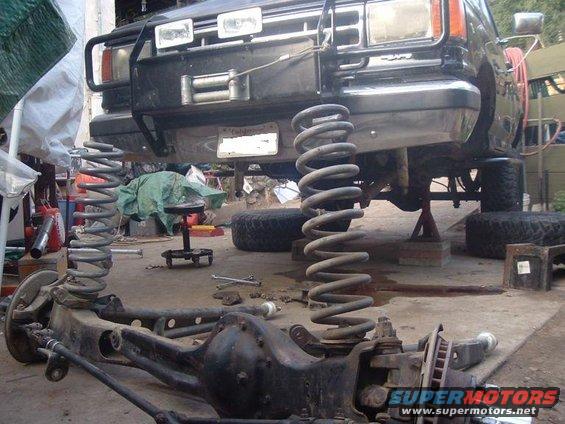 Black Ford Bronco front axle and suspension removed, lifted on jack stands