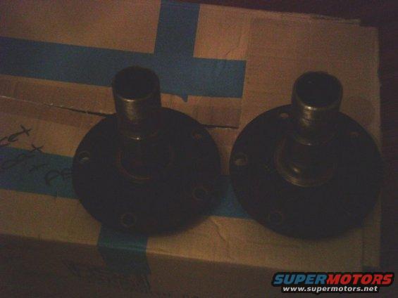 Two dark-colored wheel hubs with bolt holes on a cardboard box