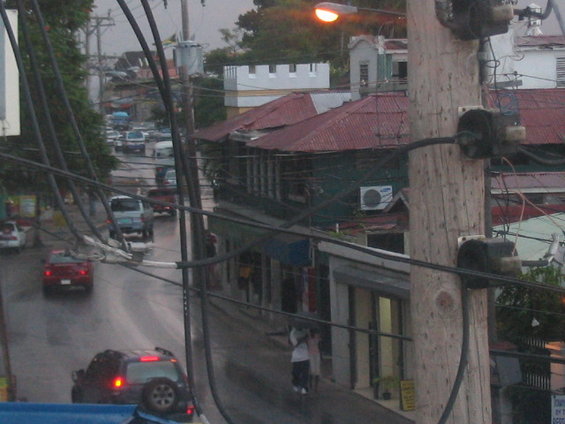Street with multiple cars and buildings, power lines in foreground