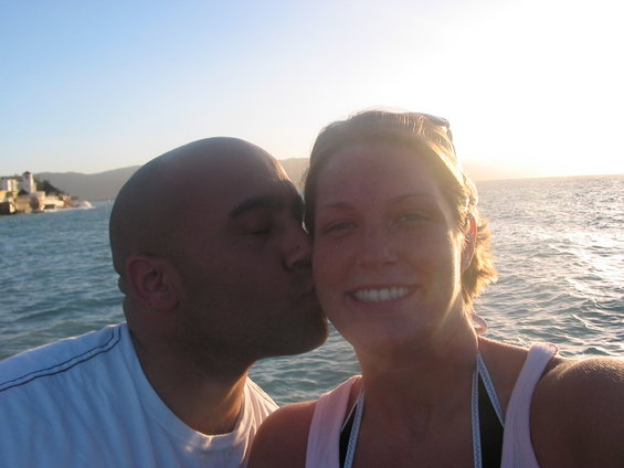 Couple kissing with ocean and buildings in background