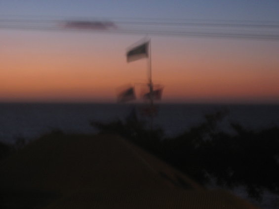 Boat with flag on the water at sunset