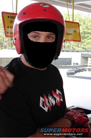 Person wearing a red helmet and black face mask, black t-shirt with red and white flame graphics, and red bandana-patterned gloves