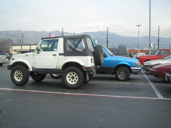 White Suzuki Samurai parked next to a blue Ford Ranger in a parking lot
