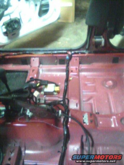 Red car interior chassis with exposed wiring and metal frame. A Supermotors.net logo is visible in the lower right