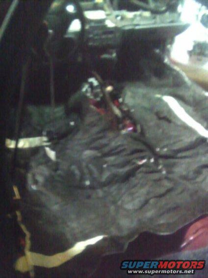 Car interior with black fabric covering the dashboard and center console. Red and yellow wires are visible