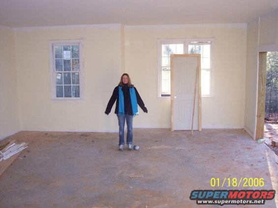 Interior scene with a person standing in an unfinished room with windows and a door