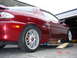 1993 Mazda MX-3 - A red coupe is parked on ramps in front of a garage, with a date stamp visible in the lower right corner.