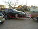 1993 Ford Taurus - A green sedan is loaded onto a trailer, hitched to a brown pickup truck, with two men observing.