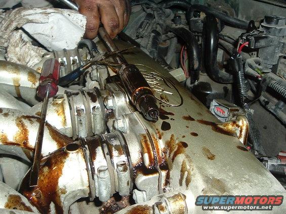 Close-up of engine component covered in oil, with tools nearby