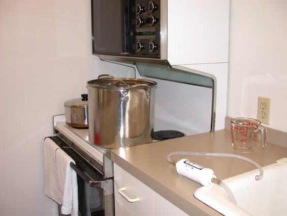 kitchen counter with pots on stove, microwave above, and a water filter device