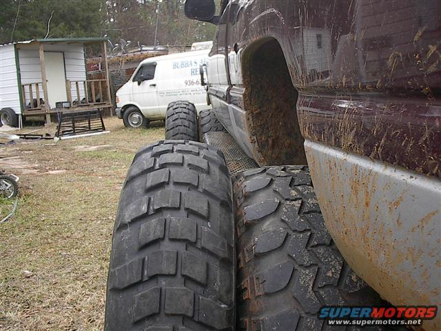 Maroon truck side view, showing large off-road tires and mud splatter