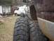 2001 Dodge 1500 - A maroon truck with large tires is parked next to a white van in a yard.