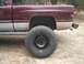 2001 Dodge 1500 - This pickup truck features a two-tone maroon and silver paint scheme and is equipped with oversized off-road tires.
