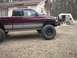 2001 Dodge 1500 - A lifted 2001 Dodge 1500 pickup truck is parked in a grassy yard next to a house and a tent.