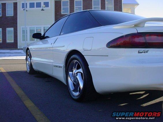 White 1996 Ford Probe coupe with spoiler, chrome wheels, and tinted windows parked on asphalt