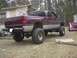 2001 Dodge 1500 - This lifted pickup truck is parked in a grassy area with a house in the background.