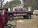 2001 Dodge 1500 - A lifted pickup truck sits in a yard next to a house, with another vehicle being worked on in the foreground.