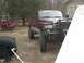 2001 Dodge 1500 - A lifted maroon pickup truck with a bull bar is parked in a yard, with a damaged red SUV in the background.