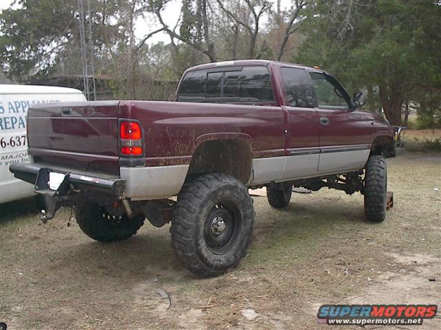 Maroon 2001 Dodge 1500 pickup truck, rear 3/4 view, lifted with large tires