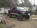 2001 Dodge 1500 - This lifted 2001 Dodge 1500 pickup truck is parked in a yard with a trailer and other structures in the background.