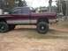 2001 Dodge 1500 - A lifted pickup truck sits on a dirt lot near a rural house, with another vehicle visible in the distance.