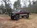 2001 Dodge 1500 - A lifted pickup truck with a custom front bumper sits on a dirt lot.