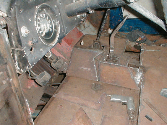 Close-up of metal floor panels, possibly for a vehicle, with bricks in the background