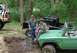 1978 Ford F-250 - Two people stand with a 1978 Ford Bronco and a black pickup truck in a wooded off-road area.
