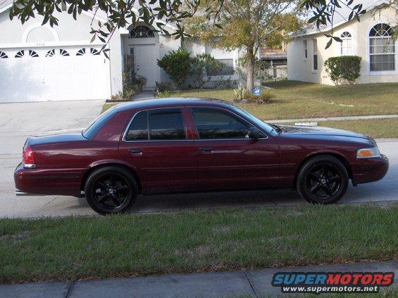 Maroon 2004 Ford Crown Victoria with black wheels parked on a residential street