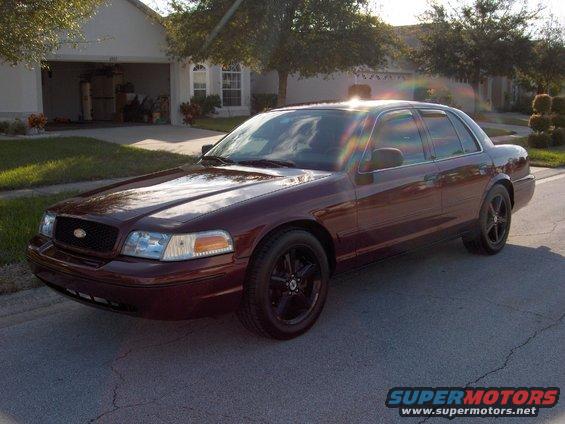 Maroon 2004 Ford Crown Victoria parked on a suburban street in front of a house