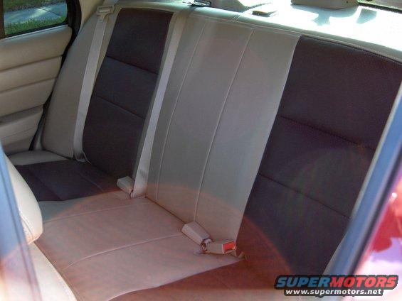 Rear bench seat with two-tone upholstery, light tan and dark brown sections, and beige seatbelts