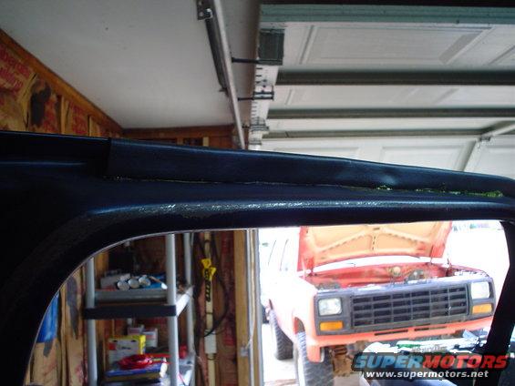 Interior trim detail with orange SUV visible through doorway