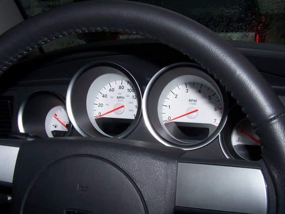 Dashboard with speedometer, tachometer, and fuel gauge. Steering wheel is black leather
