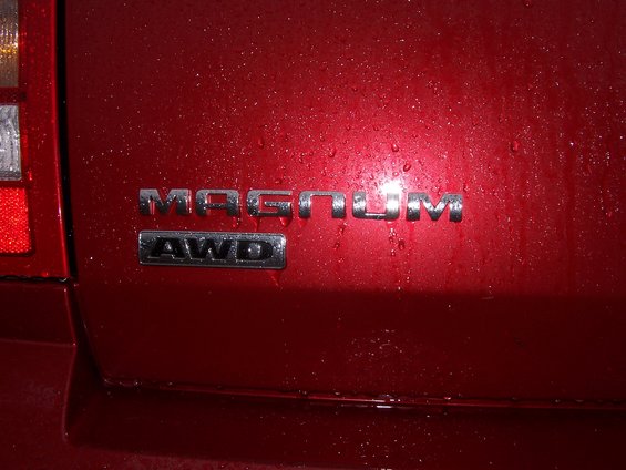Rear of red vehicle showing Magnum and AWD badges. Water droplets on surface