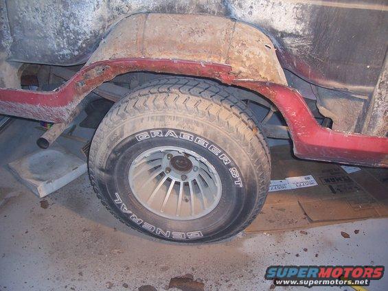 Red 1978 Ford Bronco rear quarter panel with rust and a General Grabber ST tire