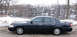 1999 Ford Crown Victoria - A dark blue Ford Crown Victoria is parked on a dirt road next to a river during winter.