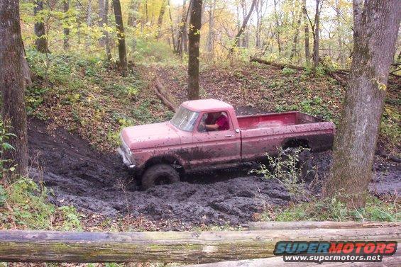 1973 Ford F-250 pickup truck, red, stuck in mud, driver visible, off-road scene