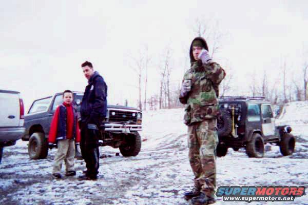 Two people stand by a lifted Ford Bronco, with a Jeep Wrangler in the background