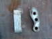1994 Jeep YJ - Two metal bracket components are shown on a wooden surface, one piece has three holes.