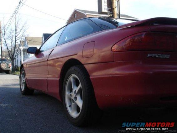 Red 1996 Ford Probe coupe, rear quarter view, parked on street, with another SUV in background